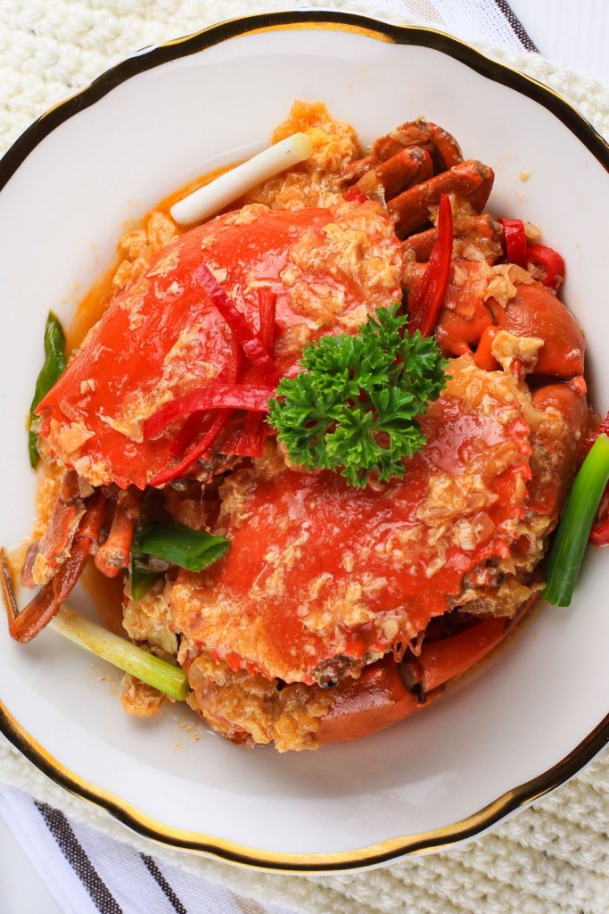Slow Cooker Sweet Chilli Mud Crab garnished with parsley in a white bowl.