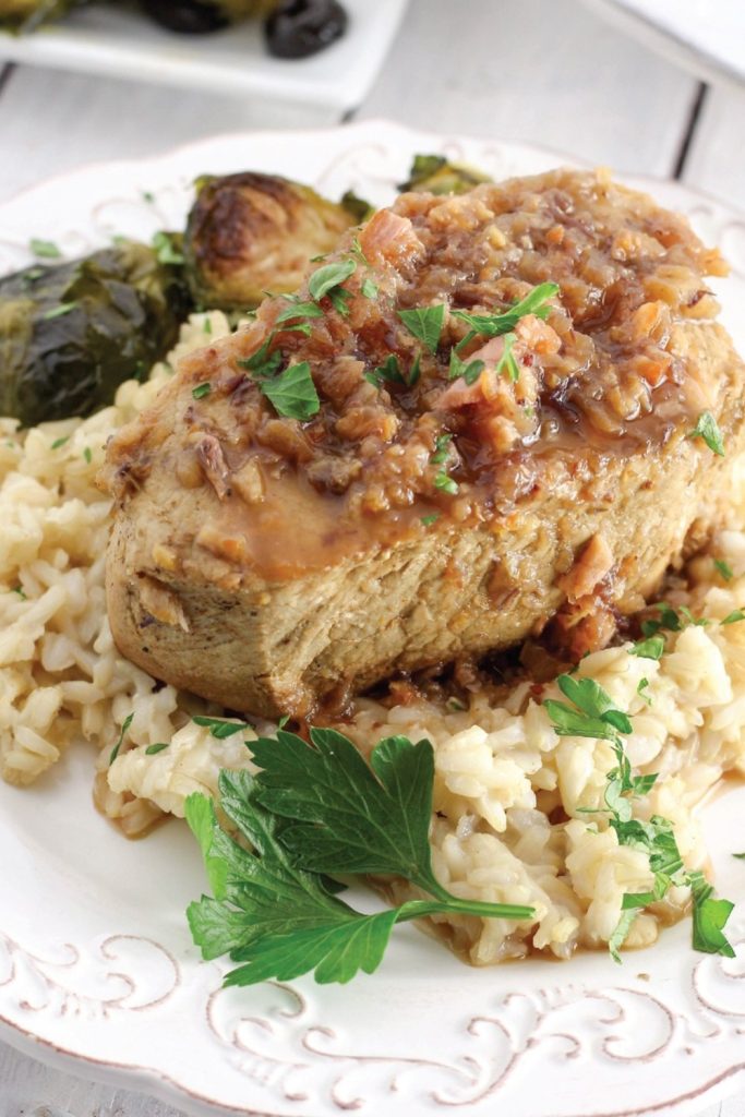 Slow Cooker Balsamic Pork Chops served over risotto with parsley garnish.