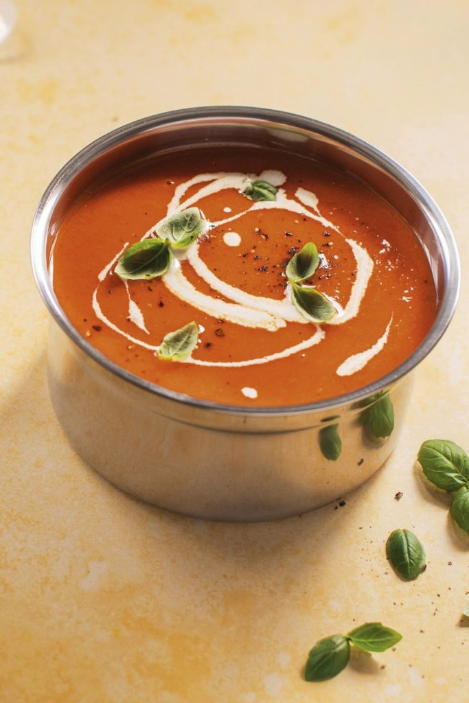 sweet potato and red pepper soup with basil garnish and cream.