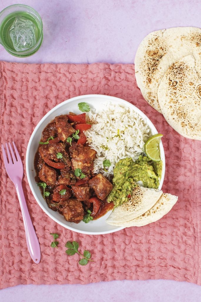 Slow Cooker Mexican Chicken Stew with rice, guacamole, and tortillas on a white plate.