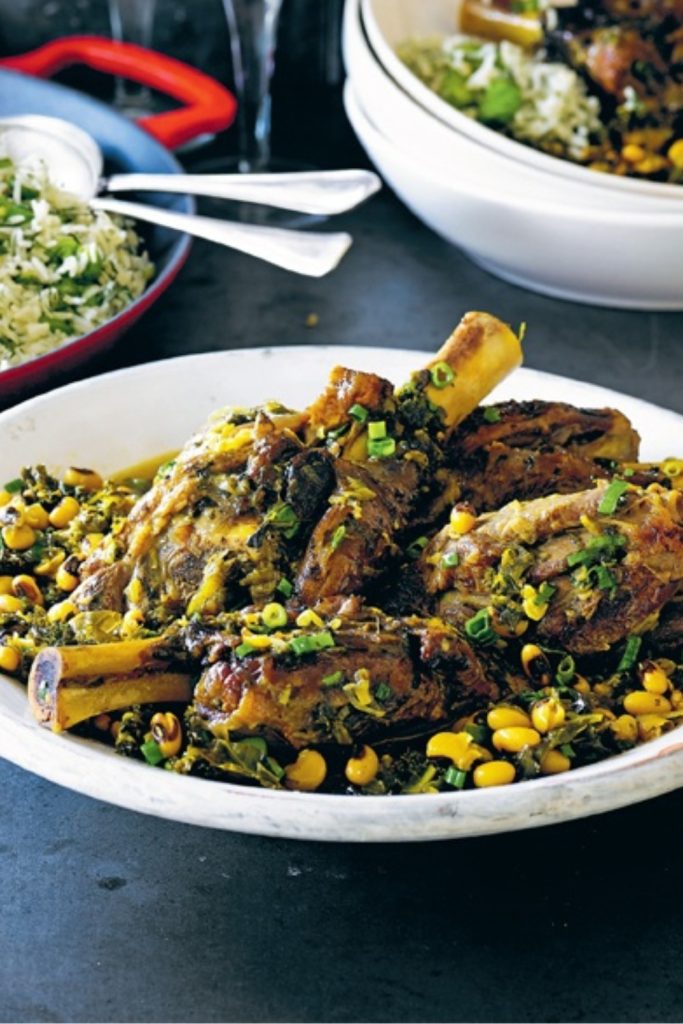 Persian Lamb Shank served in a white dish with rice and garnished with herbs.