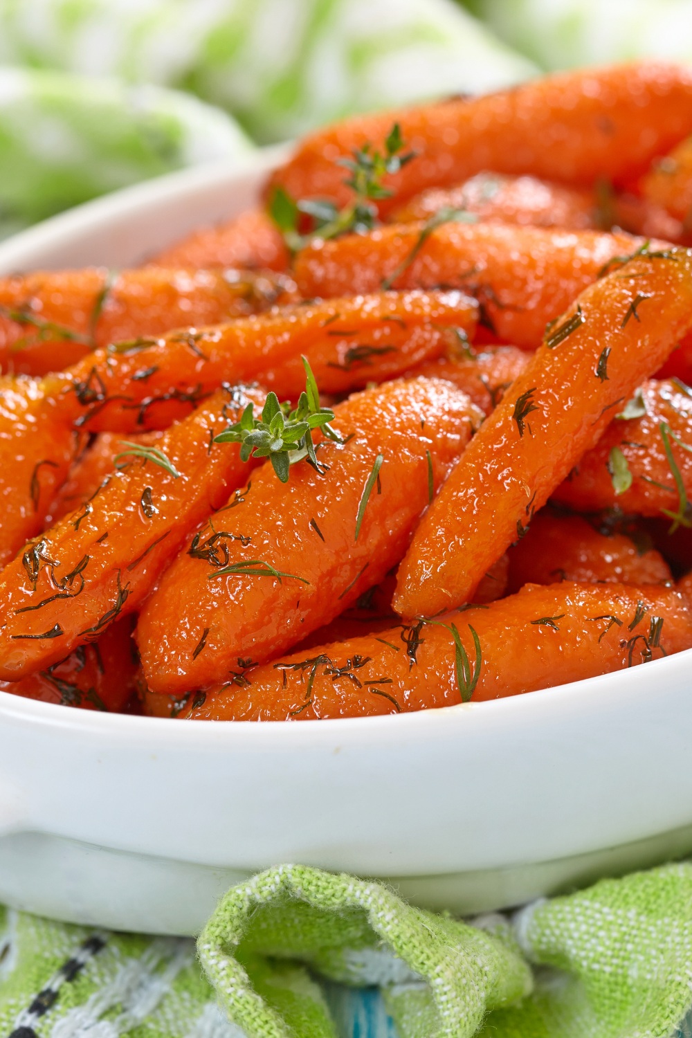 Glazed orange slow cooker carrots garnished with thyme in a white dish.