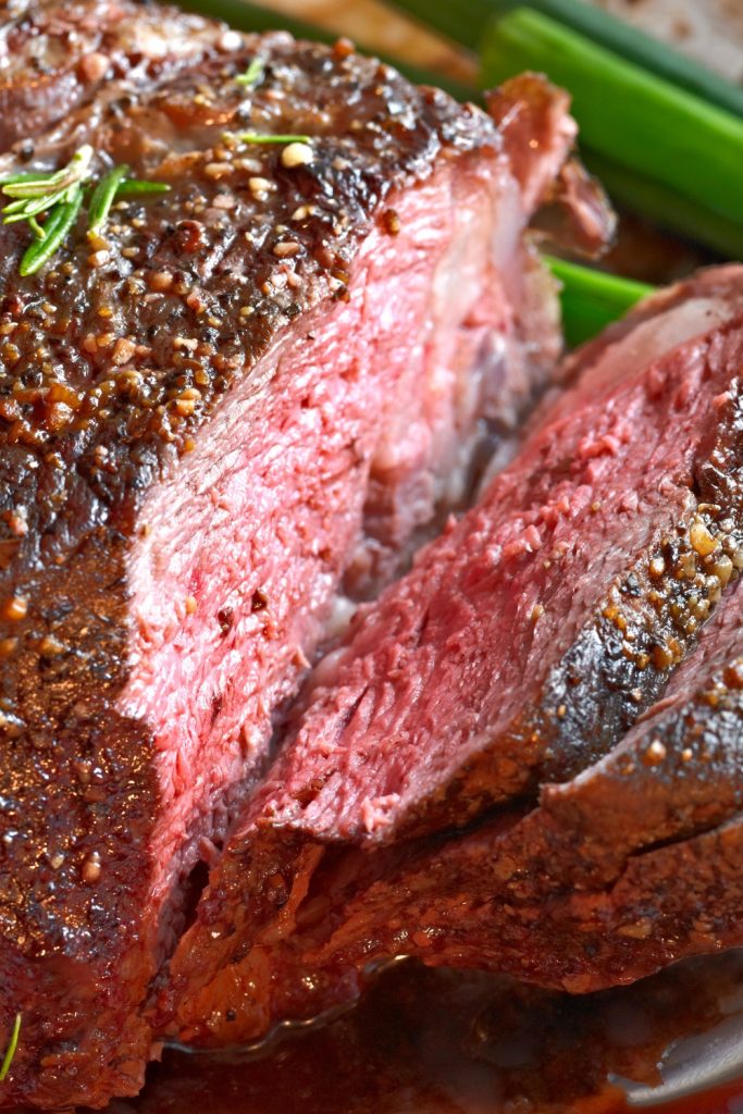 Slow-cooked kangaroo roast, sliced to show pink, tender meat with seasoning on top.
