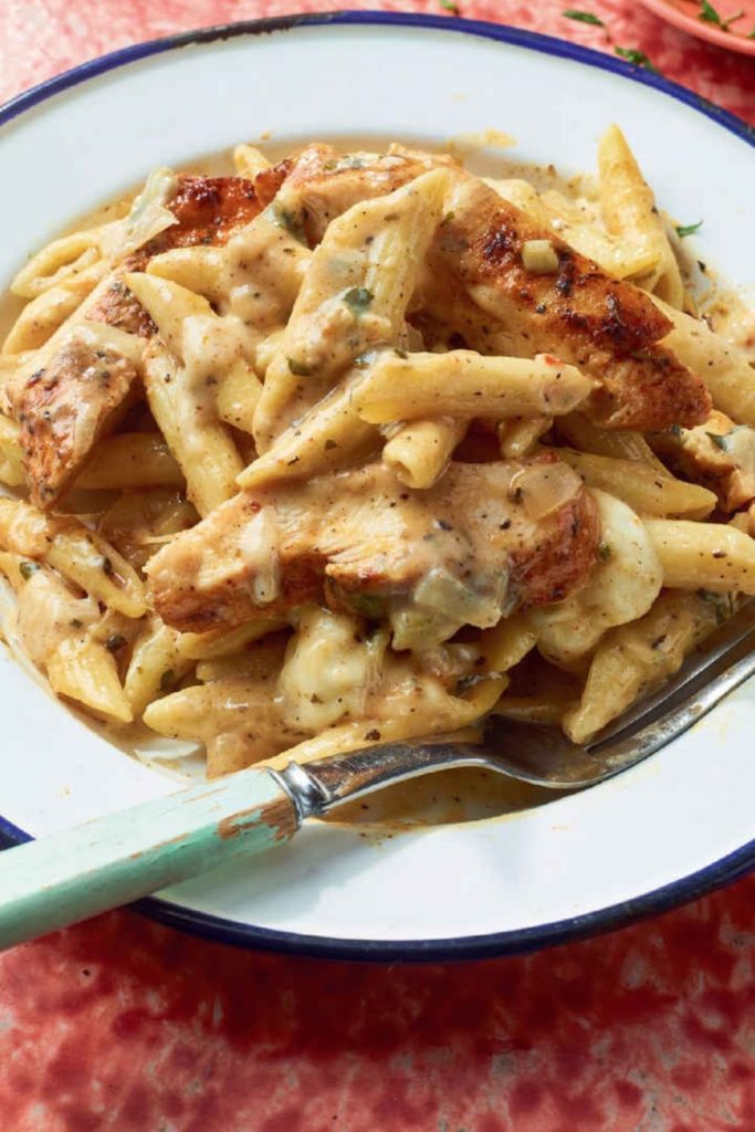 Cajun Chicken and Penne Alfredo in a white bowl with a blue rim.