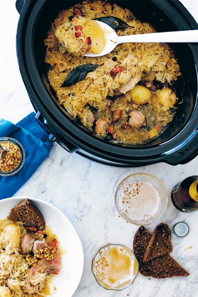 Slow Cooker Choucroute with potatoes, sauerkraut, and sausages served with mustard and bread.
