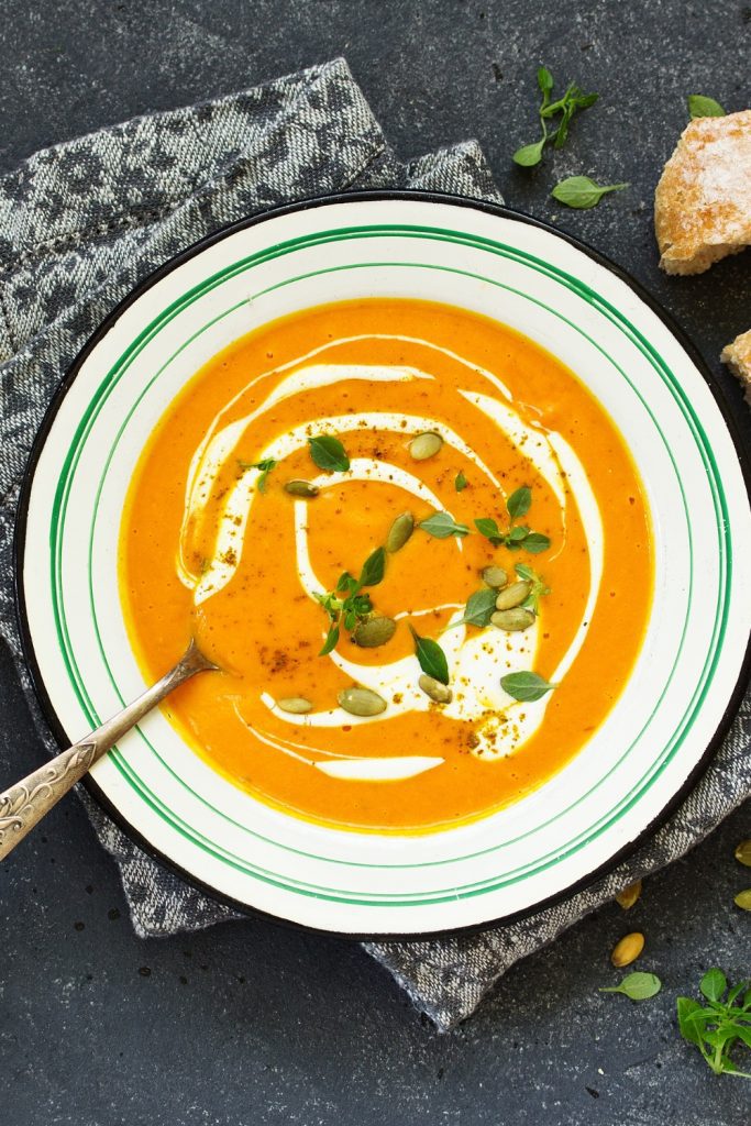 Bowl of 4-ingredient Slow Cooker Pumpkin Soup garnished with cream, herbs, and seeds.