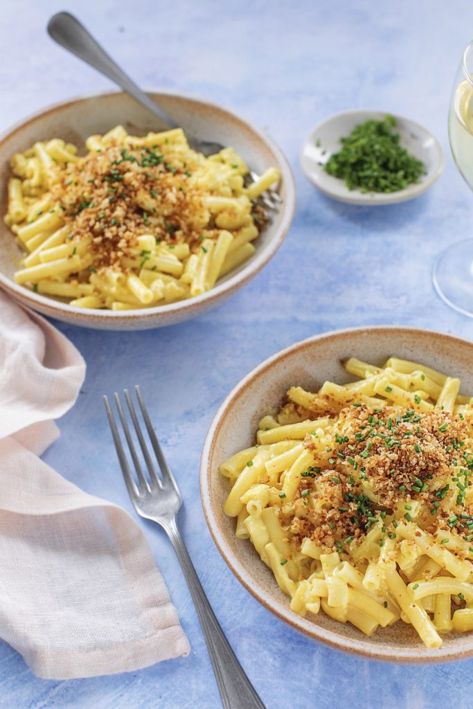 Bowls of garlic mac and cheese topped with breadcrumbs and chives.
