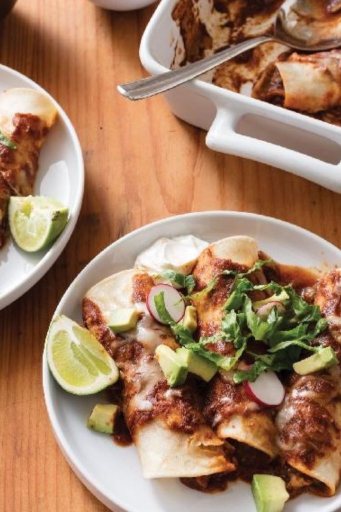 Chicken Enchilada Slow Cooker Casserole on a plate with avocado, radish, and lime.