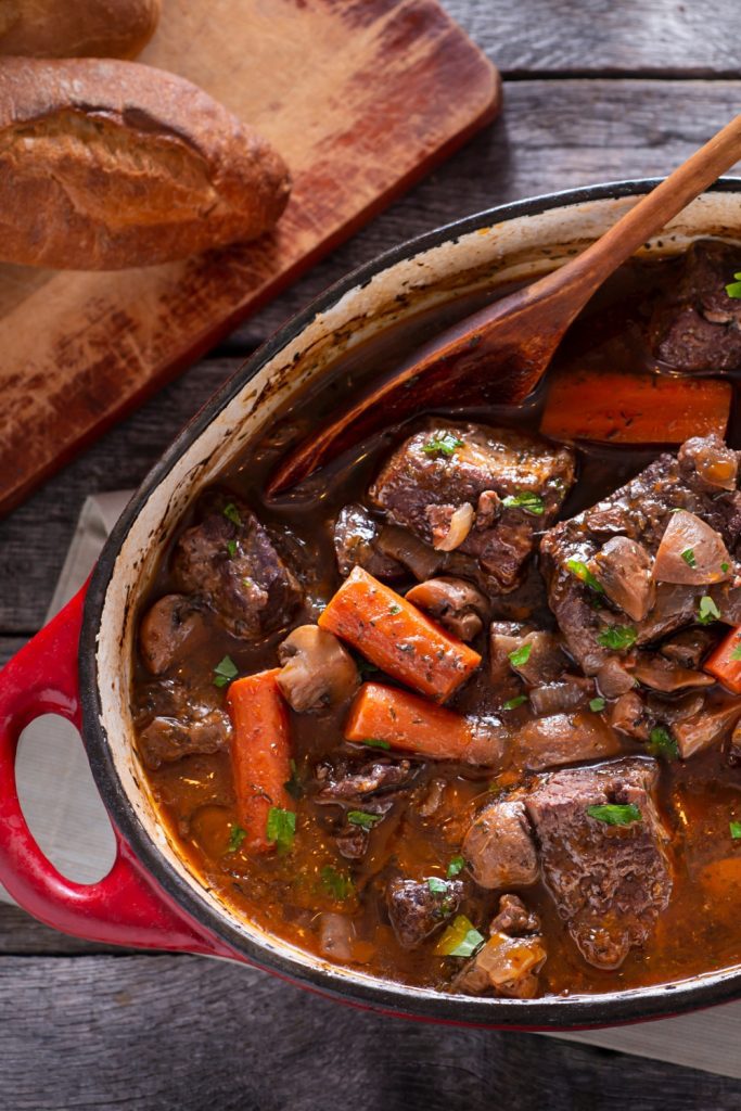 Beef and Red Wine Casserole with carrots and mushrooms served with bread.