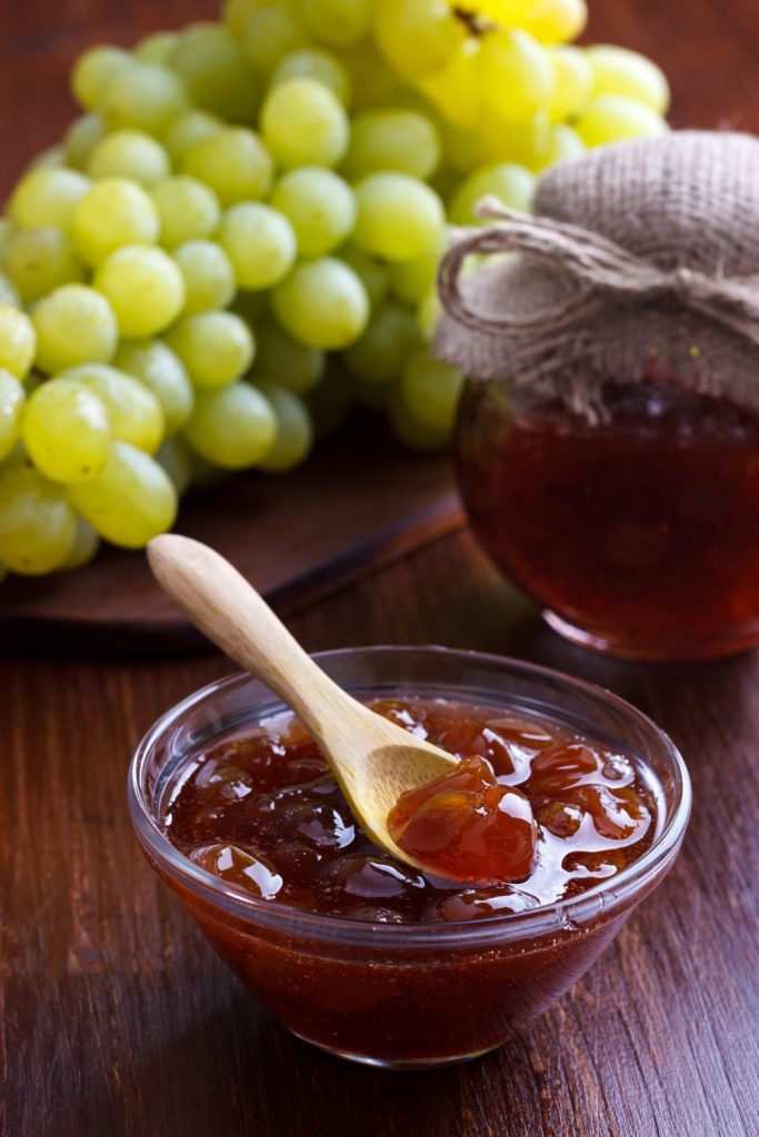 Slow Cooker Grape Jam in a jar with fresh grapes.