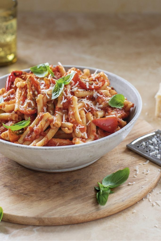 Bored of Lunch Slow Cooker Pasta Arrabbiata in a white bowl with basil and cheese.