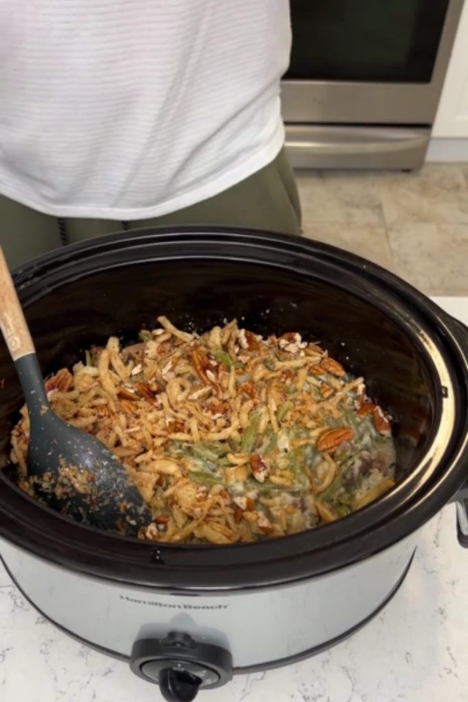 Green Bean Casserole in a slow cooker with a serving spoon.