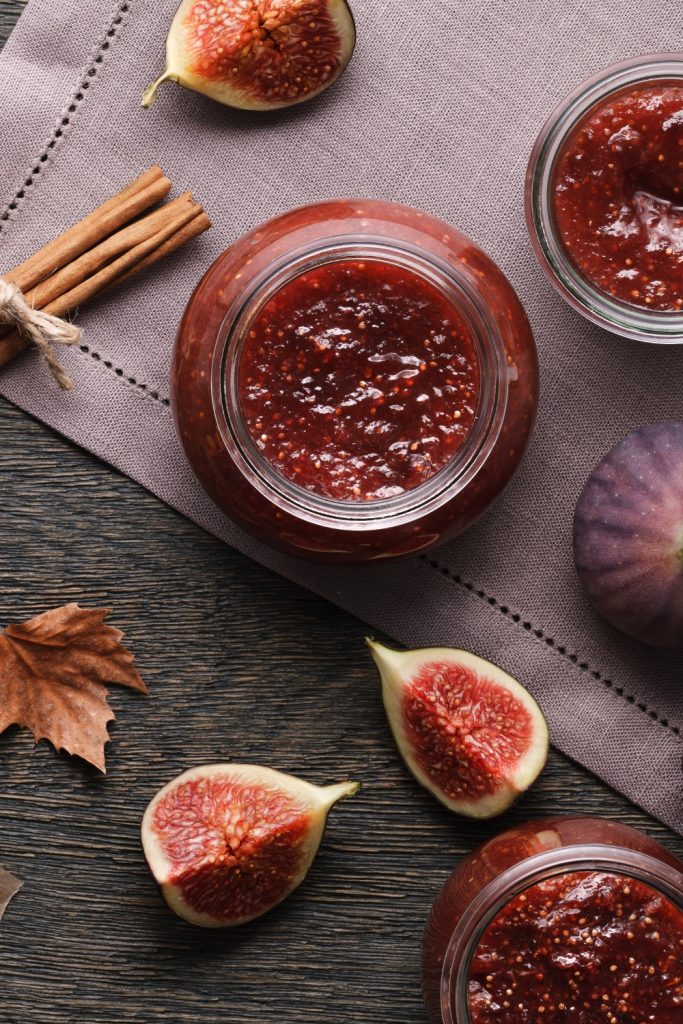 Overhead view of fig and ginger jam in jars with fresh figs and cinnamon sticks