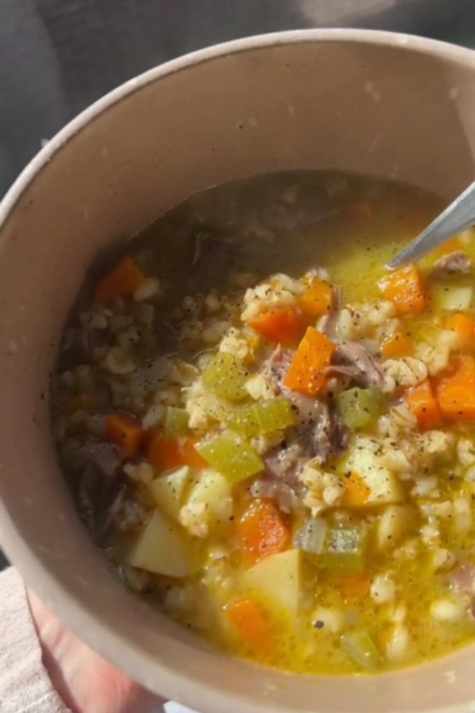 Slow Cooker Lamb Shank Soup in a bowl, highlighting the vegetables and barley.