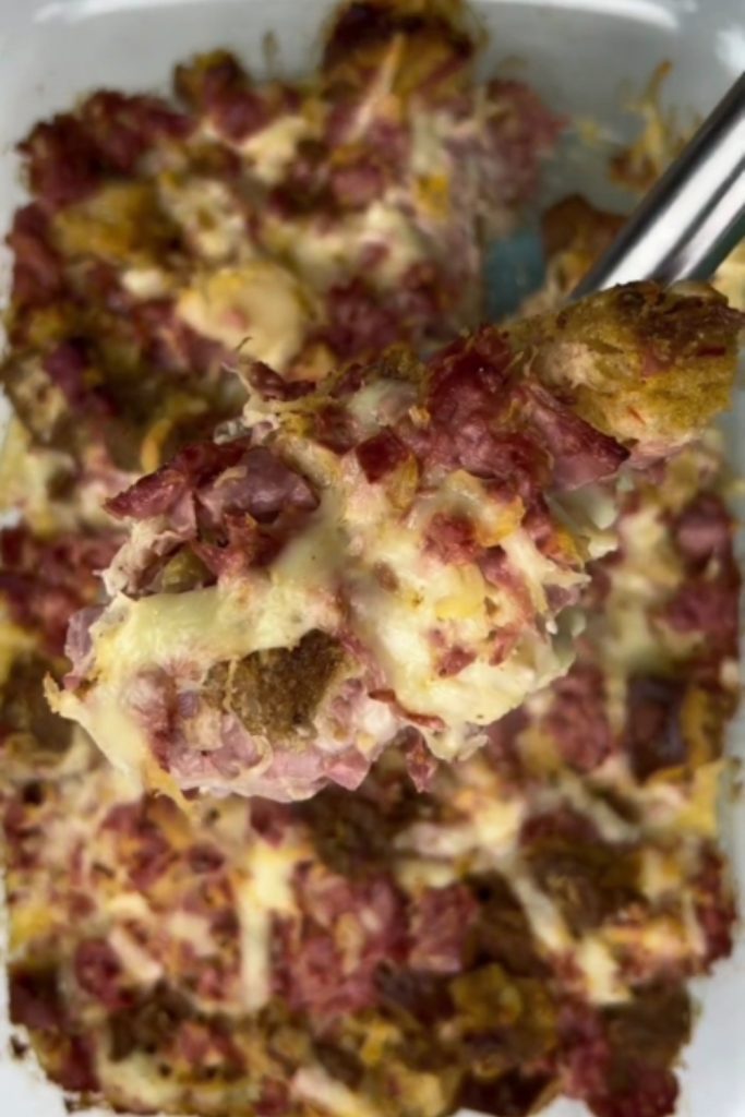 A spoonful of Reuben Casserole with melted cheese, corned beef, and sauerkraut.