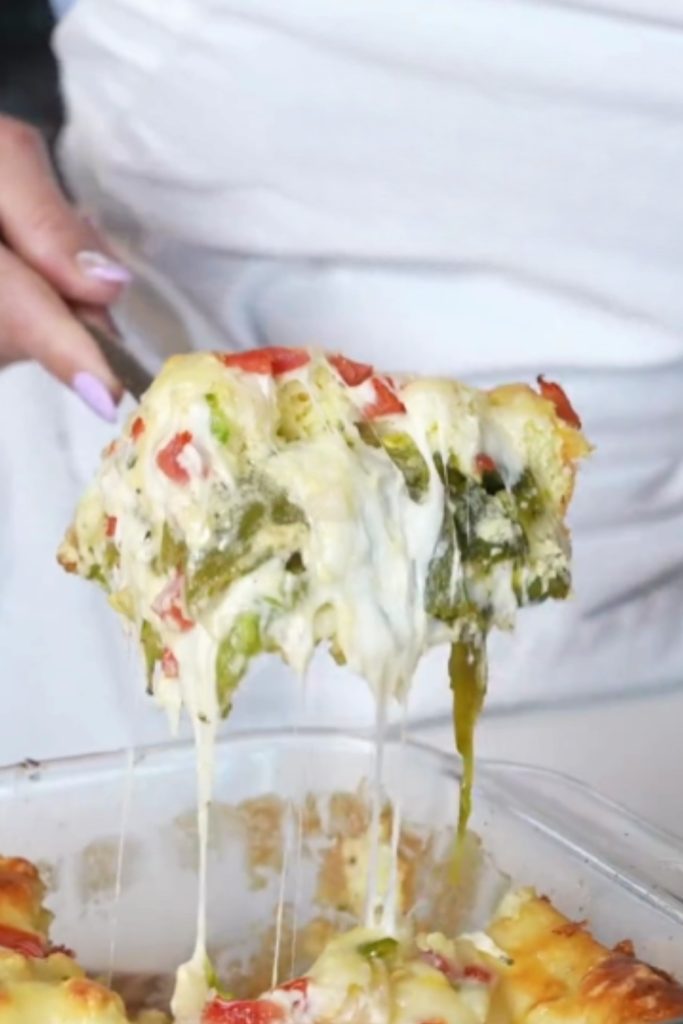 A piece of Slow Cooker Chile Rellenos Casserole being lifted from the dish with cheese and vegetables.