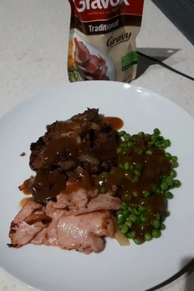 Slow Cooker Lamb's Fry and Bacon with peas and gravy, served on a white plate.