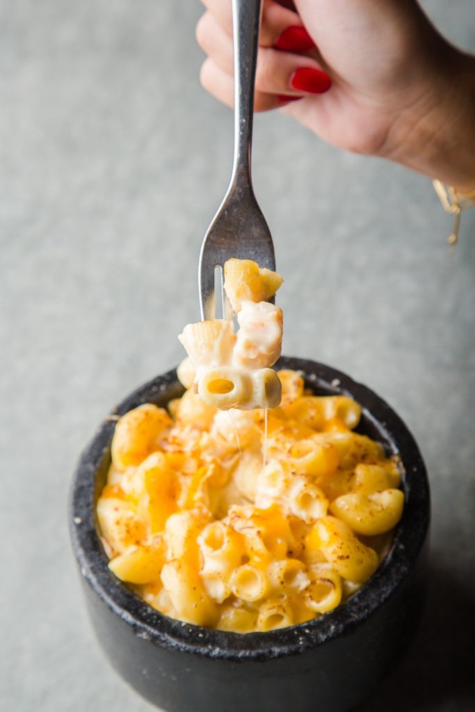 A fork lifting a bite of mac and cheese from a bowl.