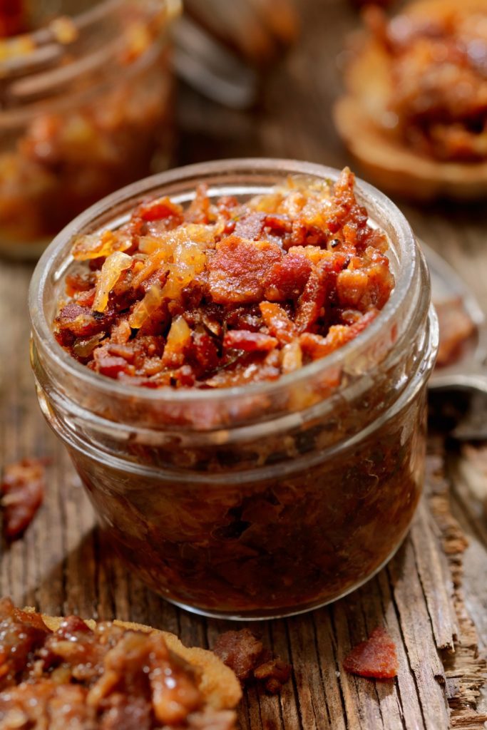 A jar of Slow Cooker Bacon Jam with crispy bacon pieces on top.