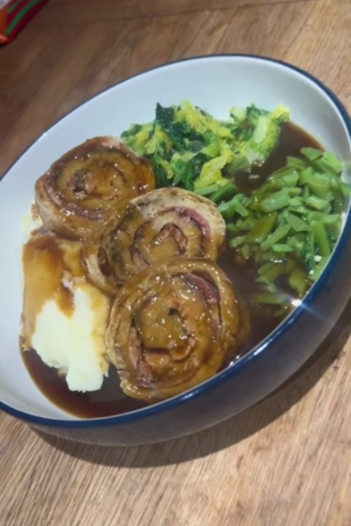 Slow Cooker Bacon and Onion Pudding with mashed potatoes, green beans, and cabbage, served in a white bowl with a blue rim.
