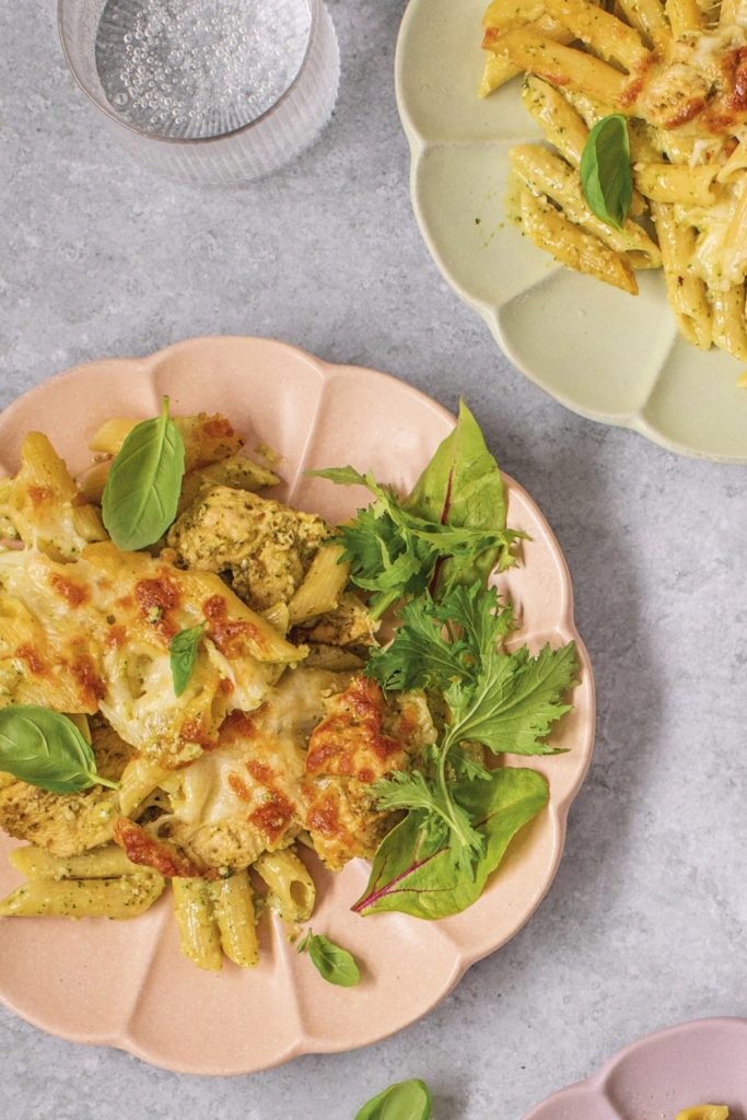 chicken pesto pasta with fresh basil on colorful plates.