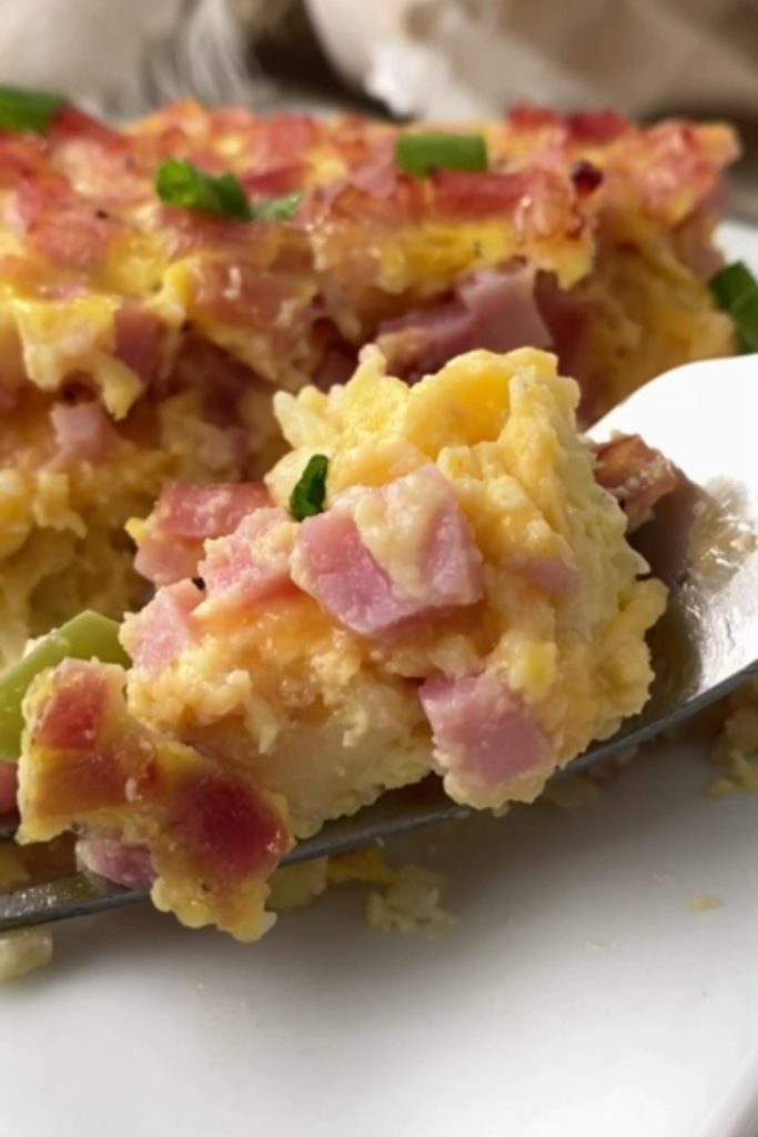 Fork digging into a slice of Ham Hash Brown Casserole.