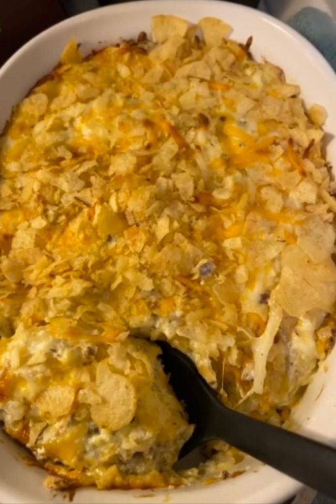 Slow Cooker Hobo Casserole with a crispy top layer and a serving spoon.