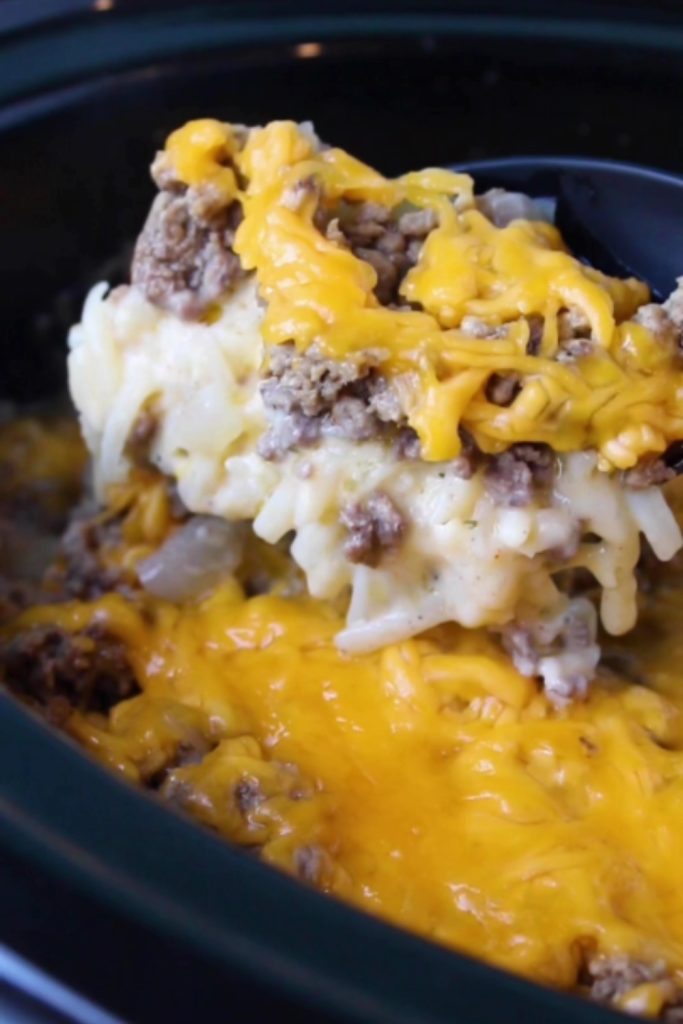 A scoop of Slow Cooker Hamburger Hash Brown Casserole with melted cheese being lifted from the slow cooker.