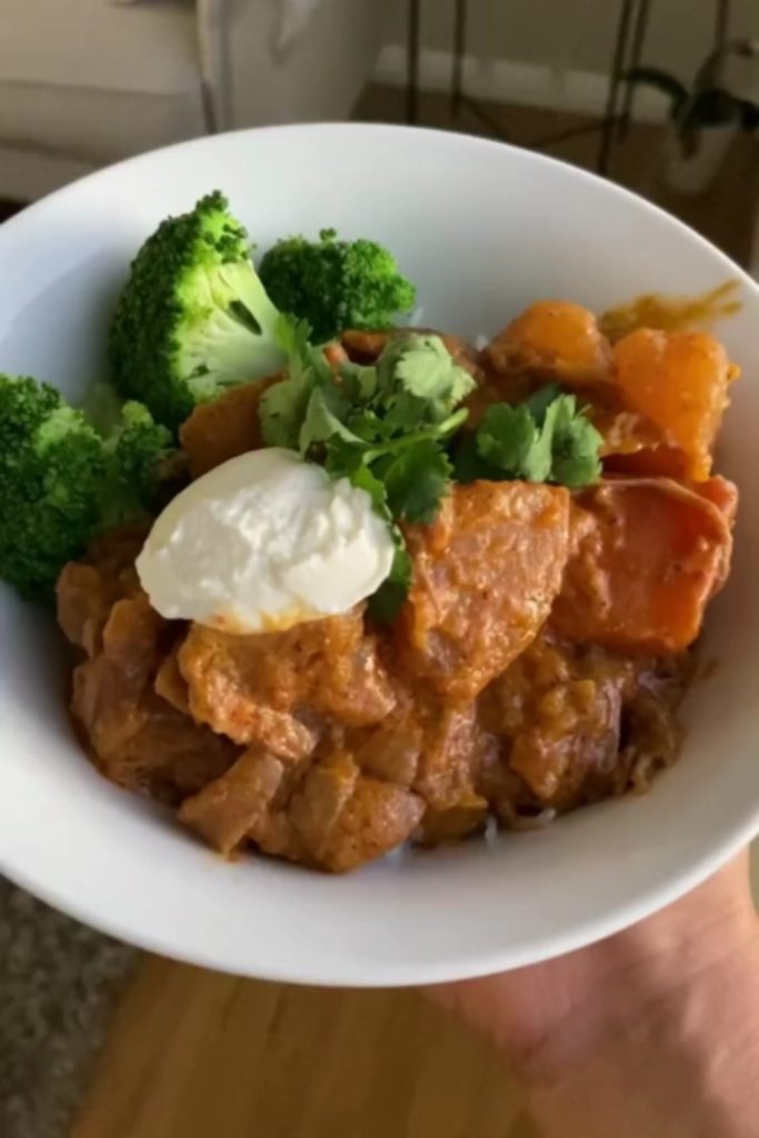 Lamb Massaman Curry in a bowl with broccoli, yogurt, and cilantro garnish.