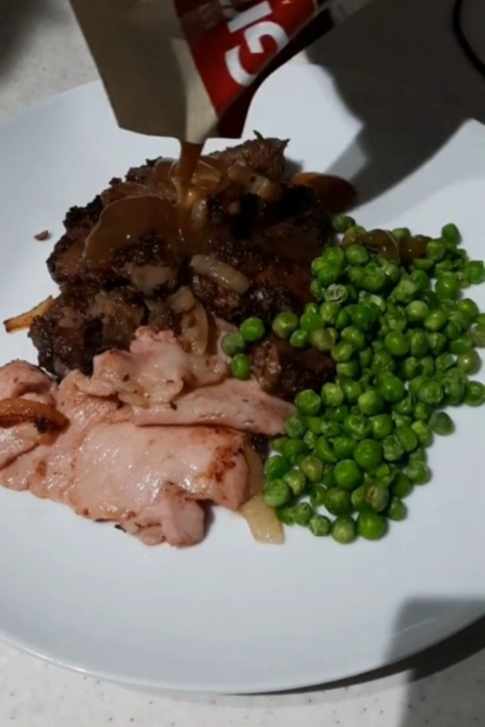 Slow Cooker Lamb's Fry and Bacon with peas and gravy being poured over the dish.