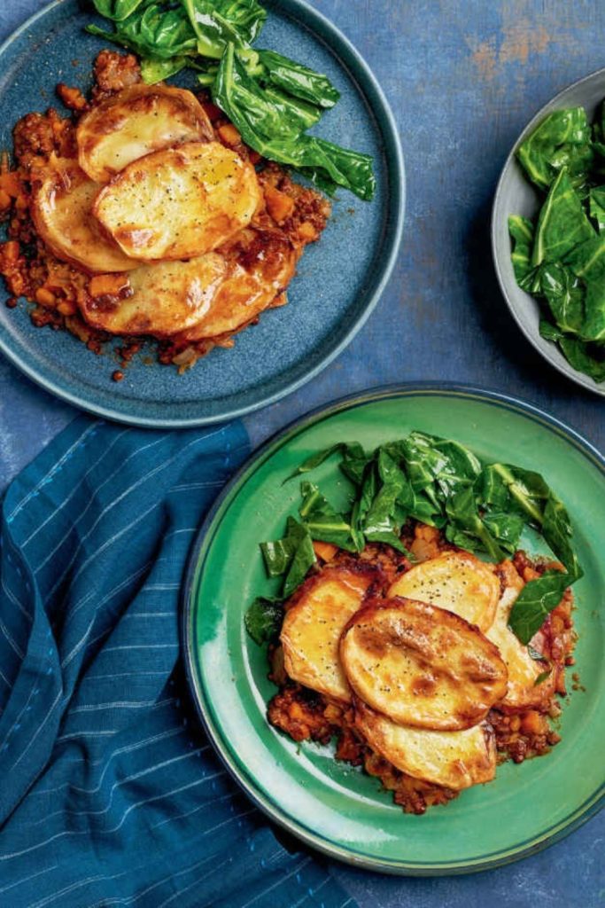 Slow Cooker Lancashire Hot Pot served on a blue plate with greens on the side.