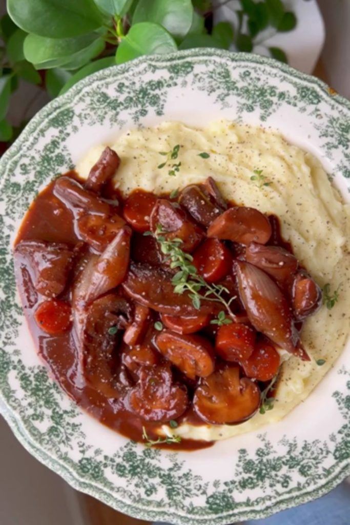 Slow Cooker Mushroom Bourguignon served over mashed potatoes on a decorative plate.