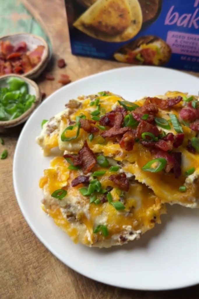 Slow Cooker Pierogi Casserole topped with cheese, bacon, and green onions on a white plate.