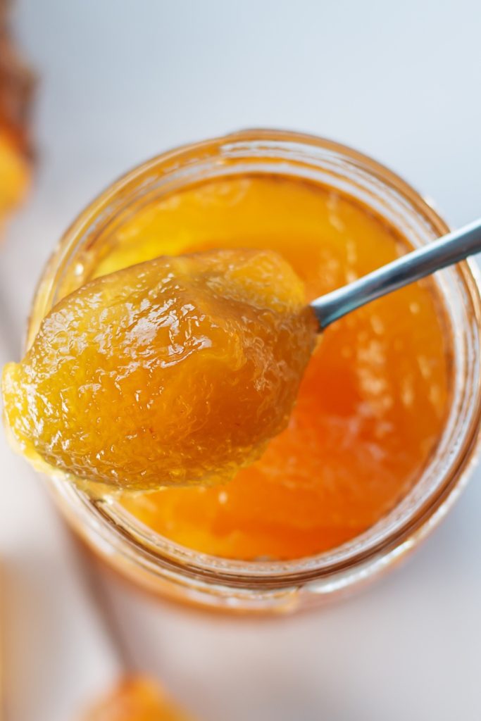 a spoonful of pineapple jam from a jar.