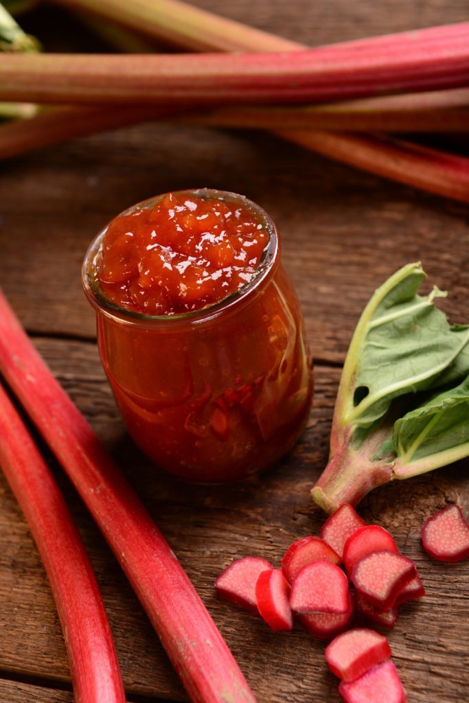 Overhead view of a jar of rhubarb jam with sliced rhubarb pieces.