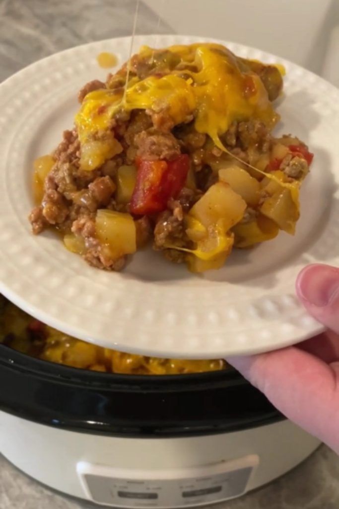  Slow Cooker Taco Casserole with melted cheese, ground beef, and red bell peppers on a white plate.