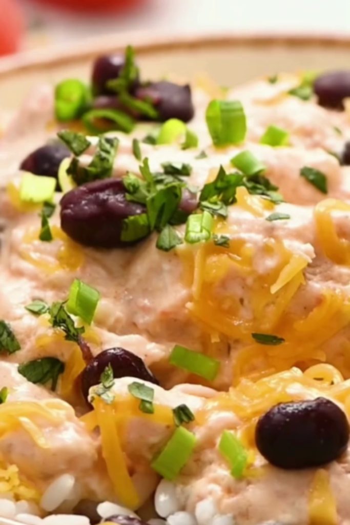 Slow Cooker Salsa Chicken topped with black beans, cheese, and green onions.