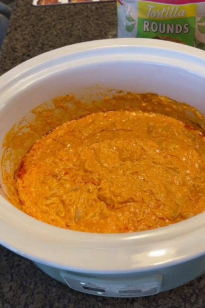 A crockpot filled with 5 Ingredient Buffalo Chicken Dip, ready to be served with tortilla chips.