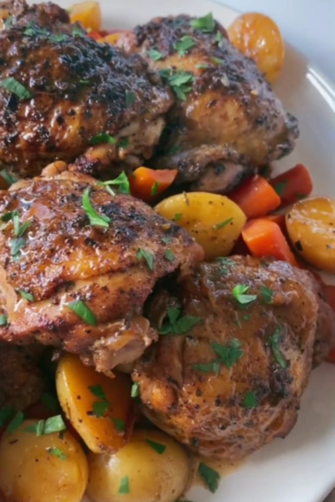 Balsamic chicken thighs with potatoes and carrots on a white plate.