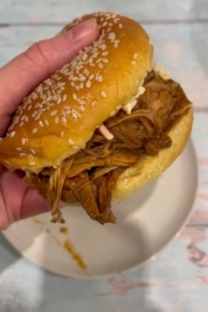 Pulled pork sandwich on a sesame seed bun.