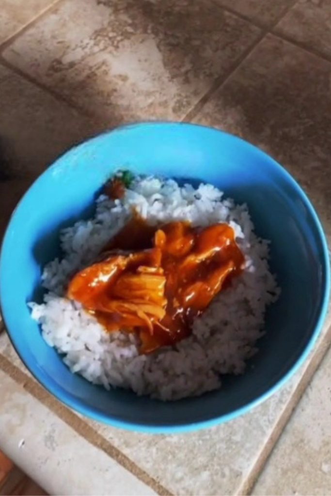 Sriracha chicken with rice in a blue bowl on a tiled countertop.