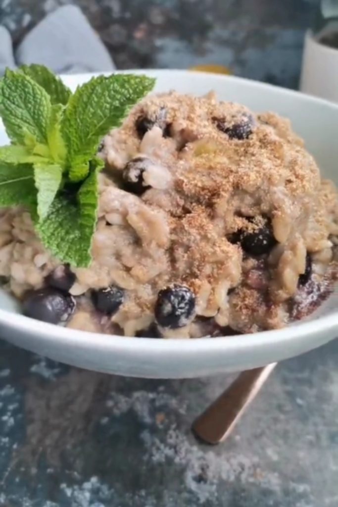 Slow Cooker Brown Rice Pudding with blueberries and a mint garnish being prepared.