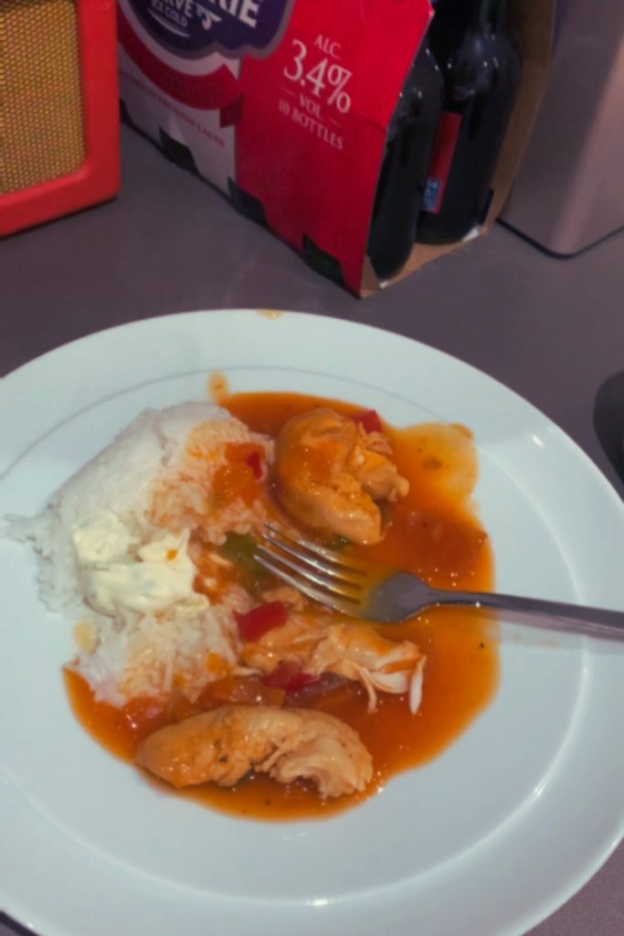 Sweet and sour chicken with rice on a white plate with a fork.