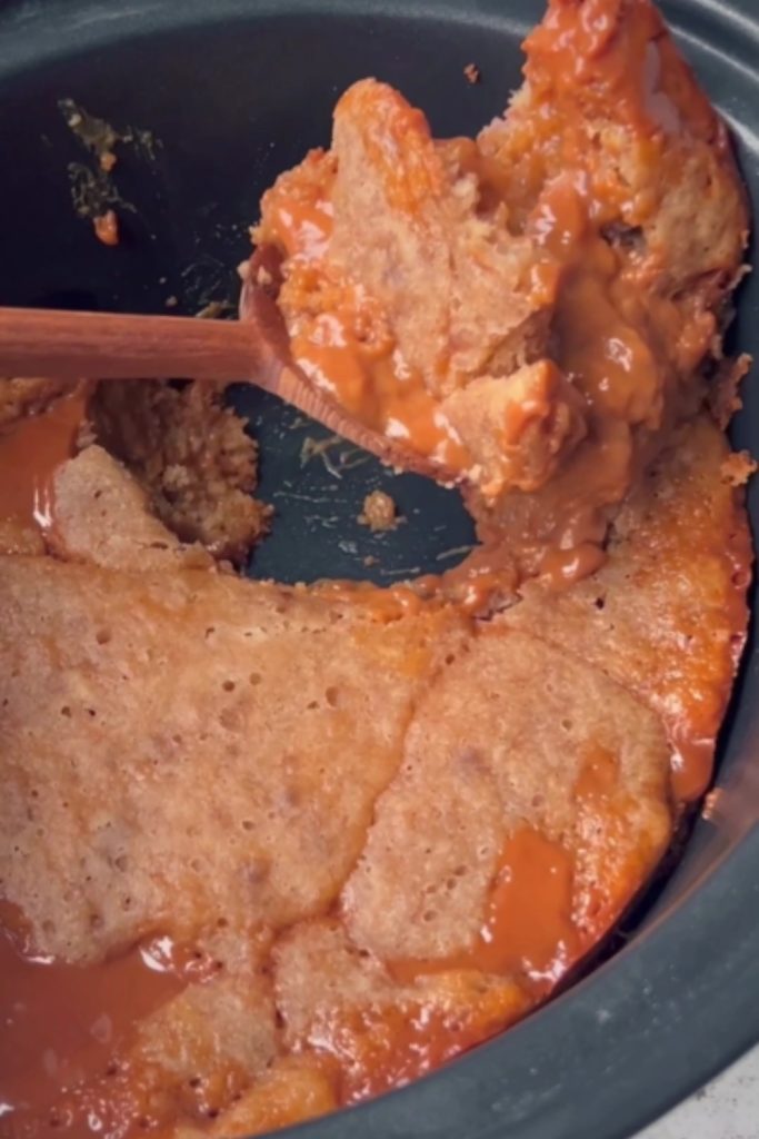 Slow Cooker Banana Bread Pudding being served from the slow cooker with a wooden spoon.