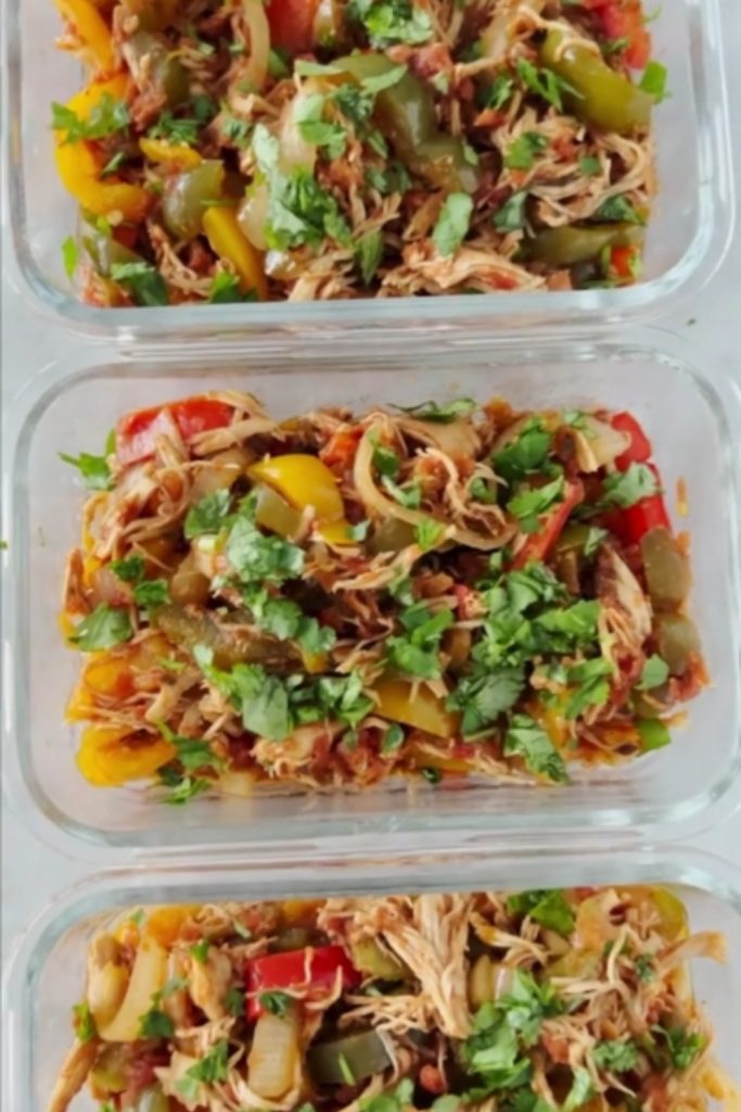 Meal-prepped chicken fajitas stored in glass containers, topped with fresh cilantro.