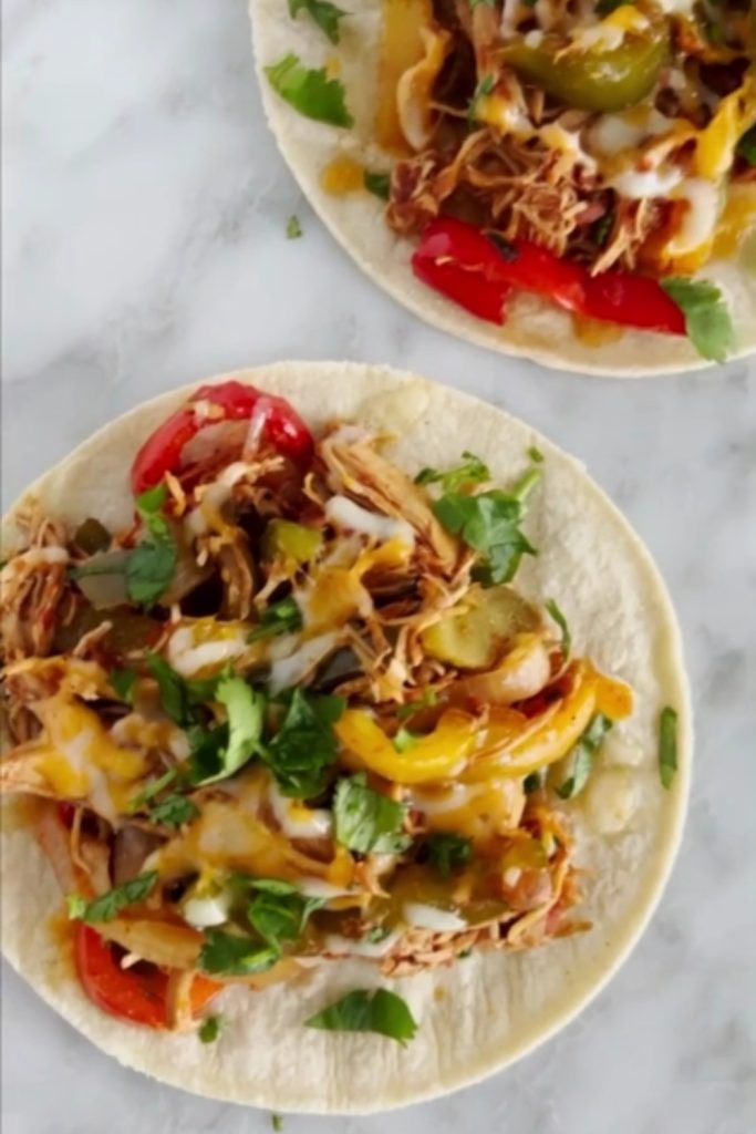 Two tortillas filled with crockpot chicken fajitas, topped with melted cheese and fresh cilantro.