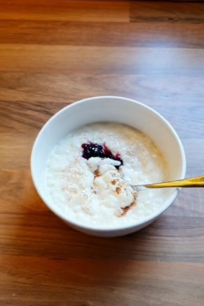 Bowl of Slow Cooker Almond Milk Rice Pudding with a spoonful lifted, topped with cinnamon and berry compote.