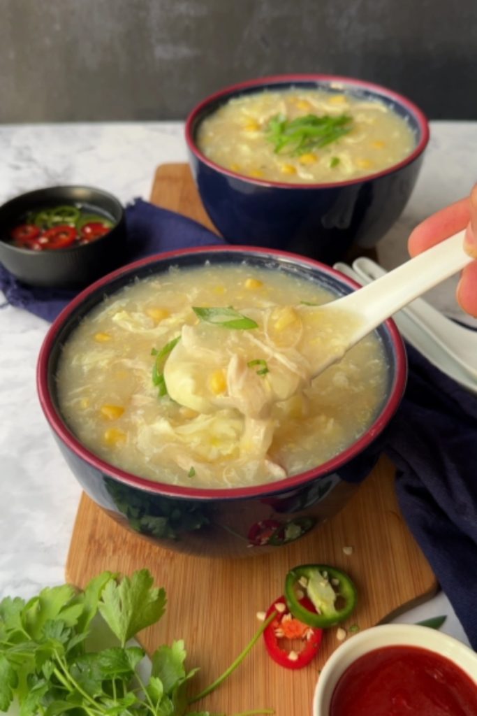 4 Ingredients Slow Cooker Easy Chicken and Corn Soup with a spoon lifting a portion from the bowl.